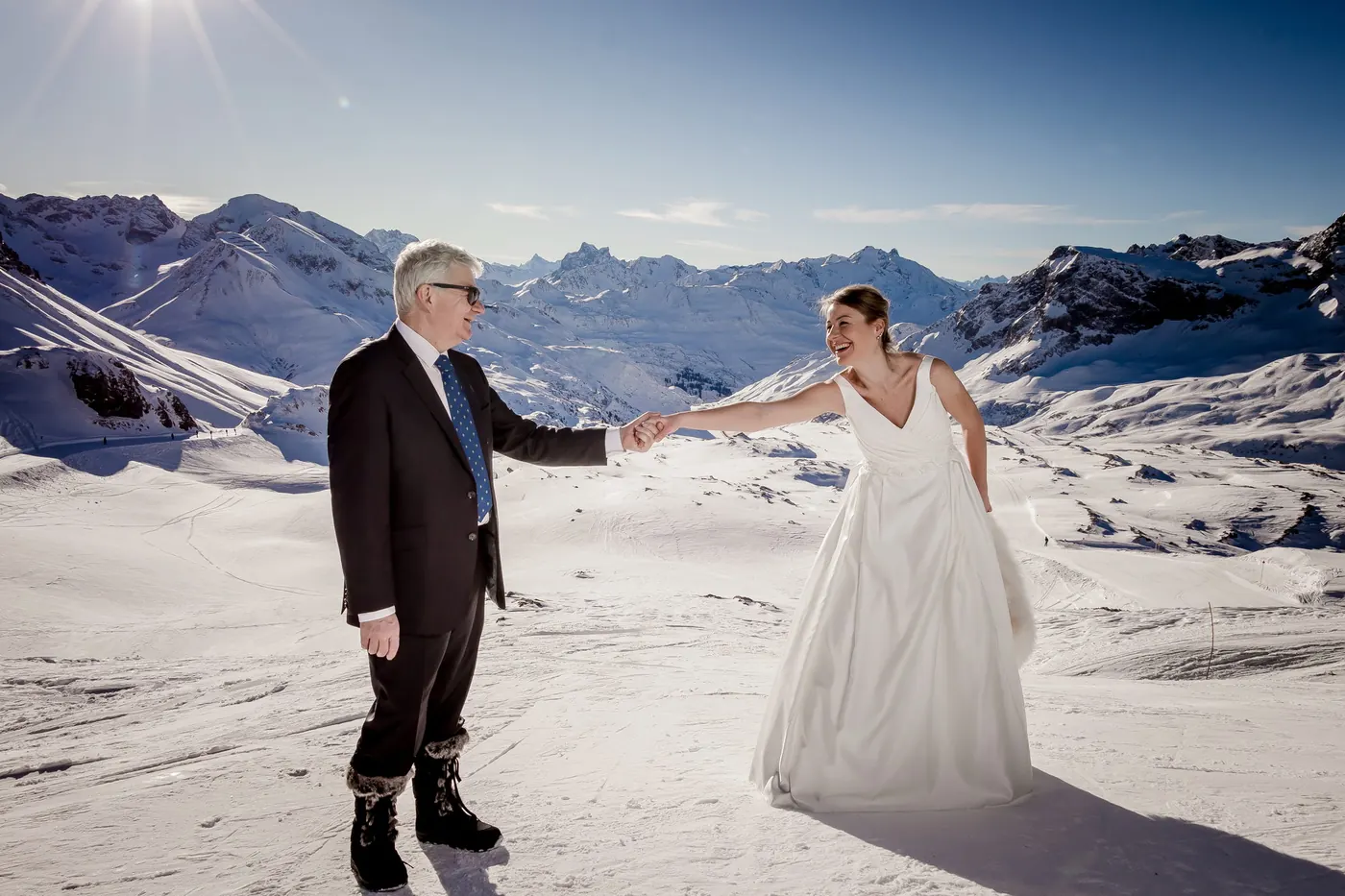 Bride and groom dancing in the snow on a mountain summit, winter wedding on the Arlberg