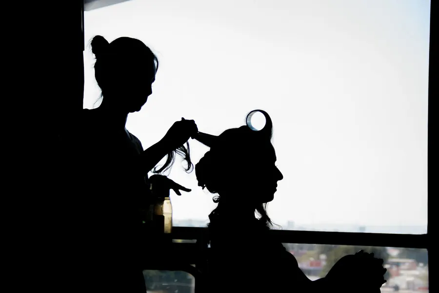 Silhouette of the bride at the window while getting ready, the morning of the wedding