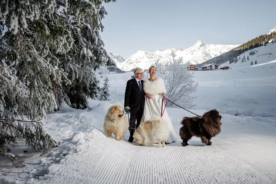 Bride and groom with three dogs in the snow, winter wedding in Lech am Arlberg