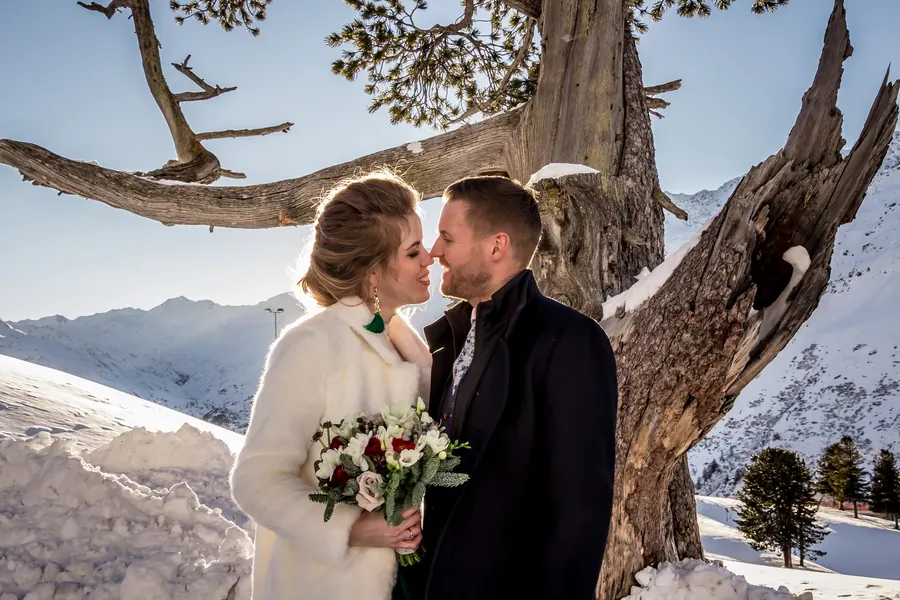 Bride and groom kissing in front of snow-covered peaks, winter wedding in Lech am Arlberg