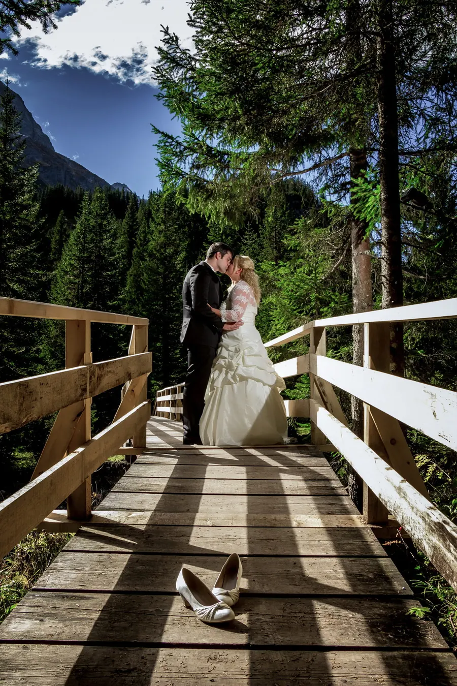 Couple kissing on a wooden bridge in a mountain forest, wedding in the Alps