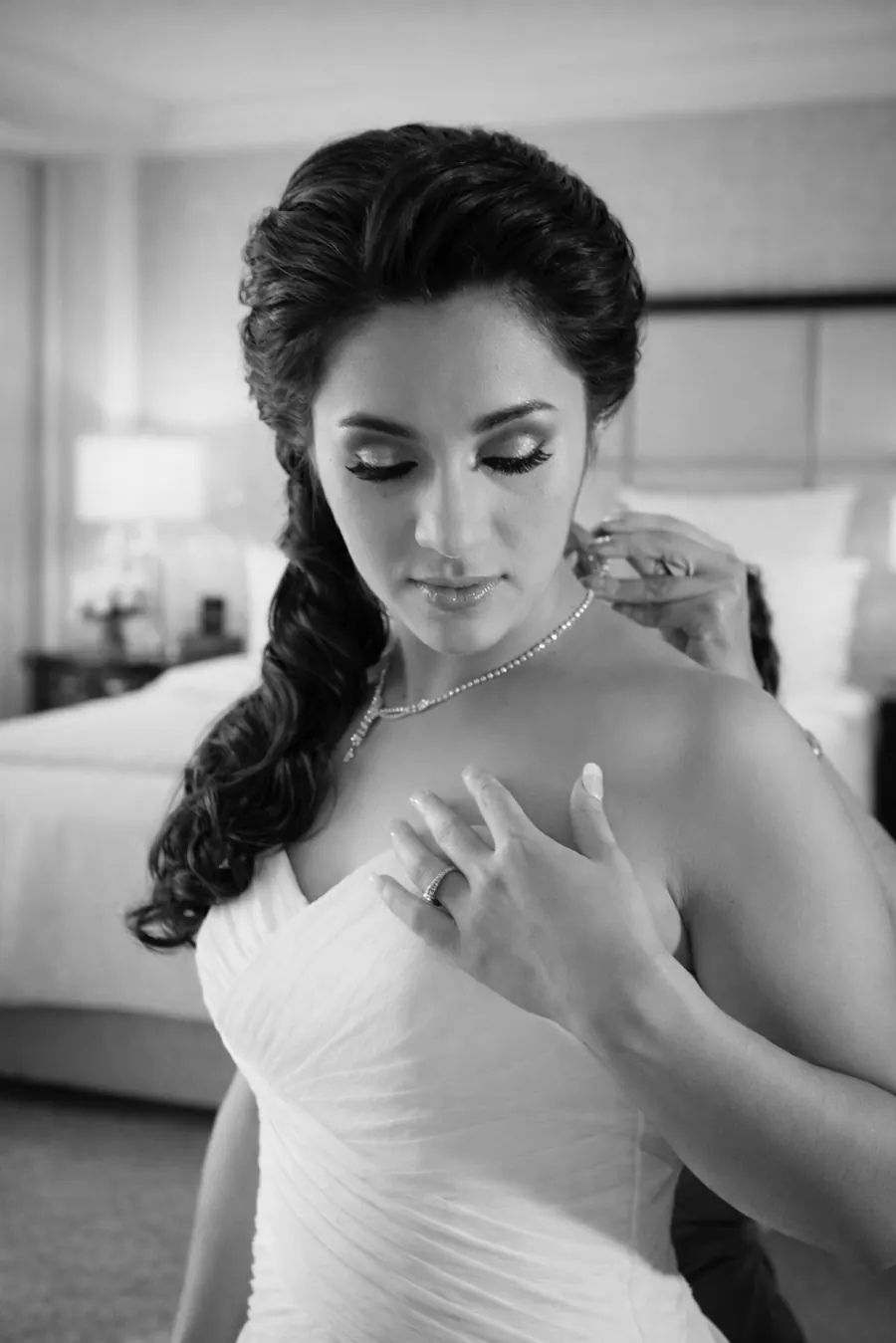 Bride fastening her necklace, a quiet moment while getting ready