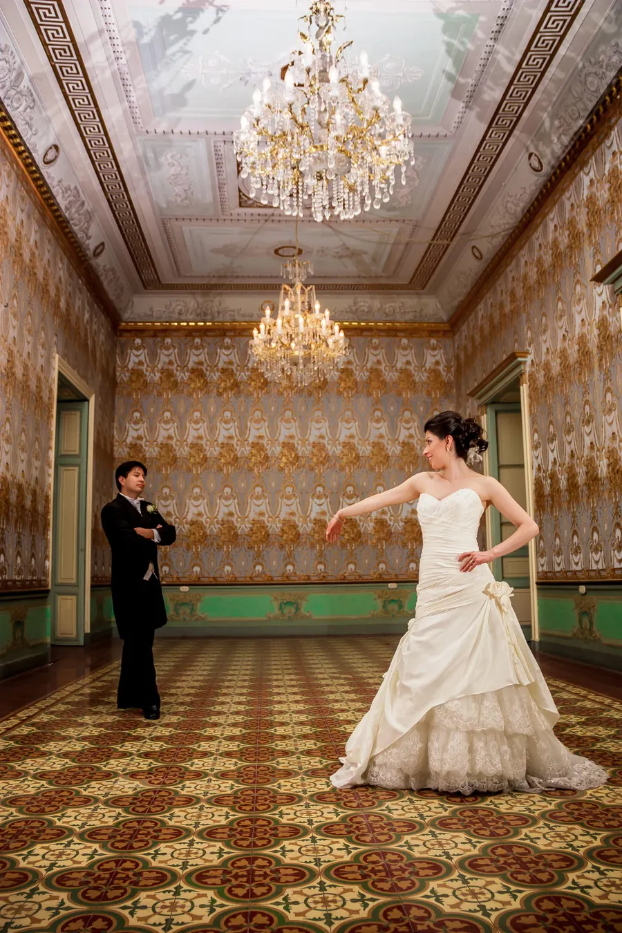 Bride dancing in a historic ballroom under crystal chandeliers, elegant castle wedding