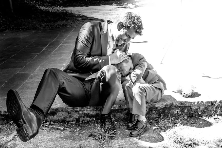 Groom comforting a small boy, an honest reportage moment in black and white