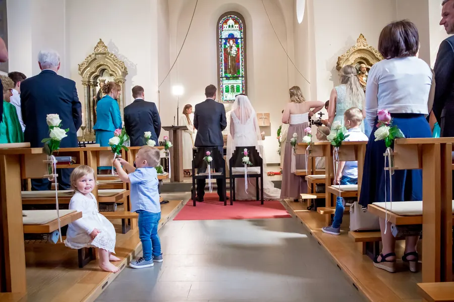 Children holding roses look towards the camera during the church ceremony in Vorarlberg
